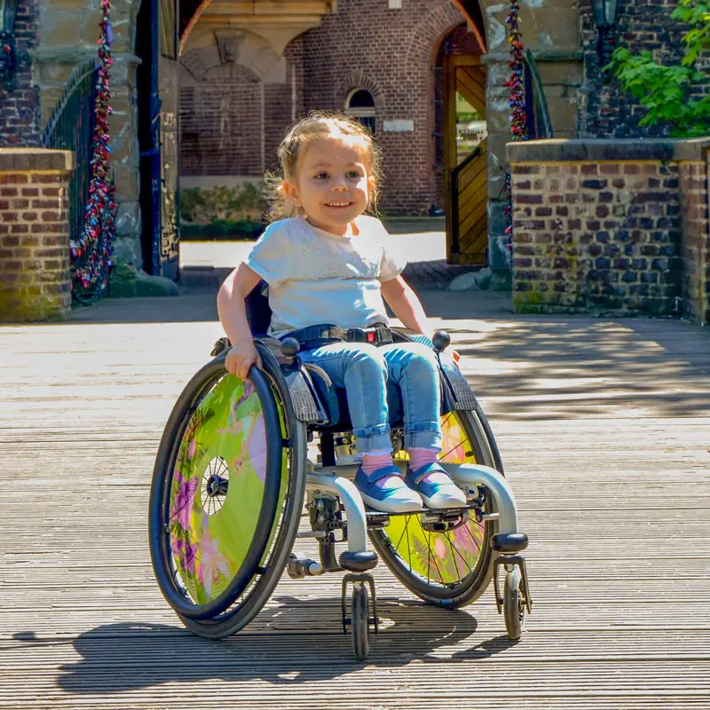 Ein lächelndes Mädchen im Kinderrollstuhl