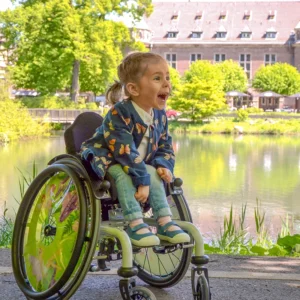 Fröhliches Mädchen im Kinderrollstuhl